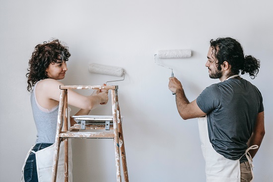 Una pareja pintando su casa